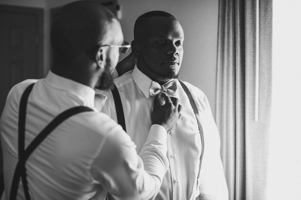 Groom getting help with his tie before his  new haven wedding 