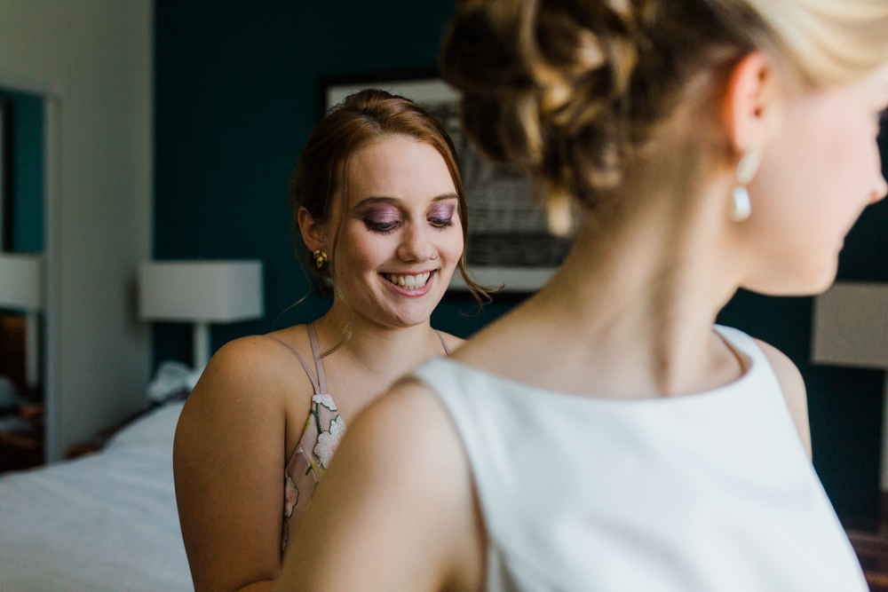 sister helping bride into her dress