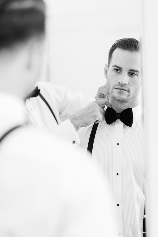Photo taken by a second photographer of a groom getting ready 