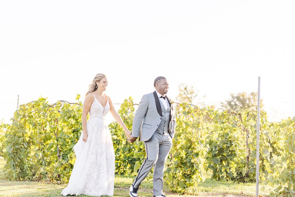 Bride and groom walking by the vineyards at their hawk ridge winery wedding