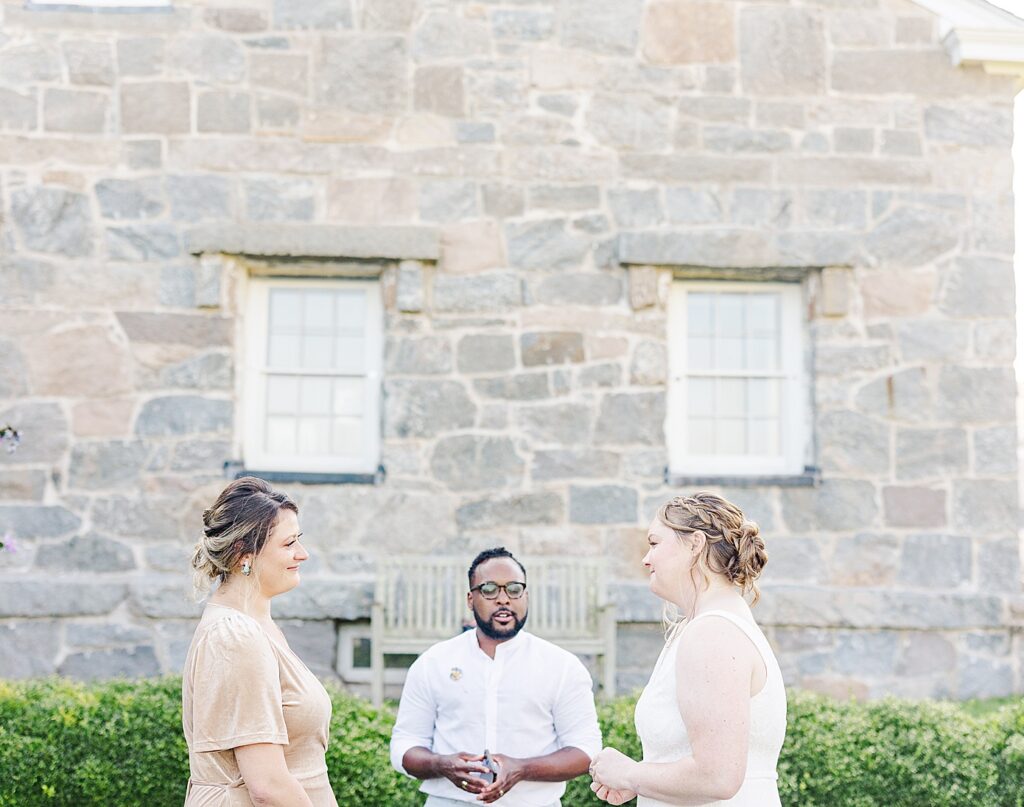 Brides exchanging vows at their mystic elopement in front of a lighthouse
